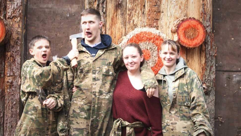 kids posing in front of axe throwing target