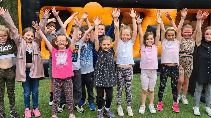 kids with arms up in front of inflatables