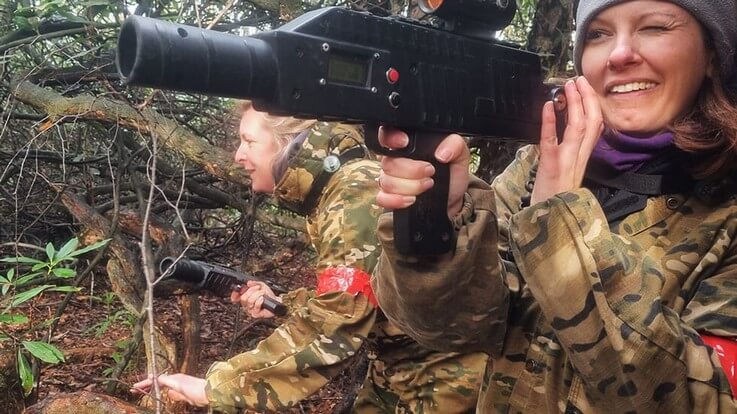 ladies playing outdoor laser tag in woodland