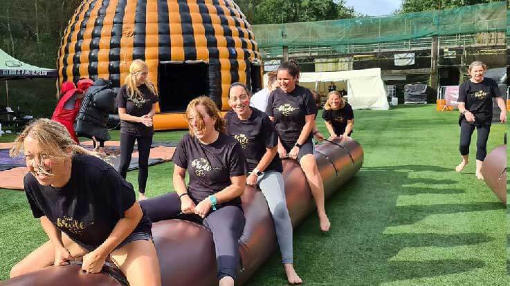 ladies riding the wobbly sausage inflatable