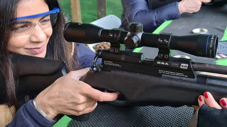 lady rifle shooter taking aim from seated-position