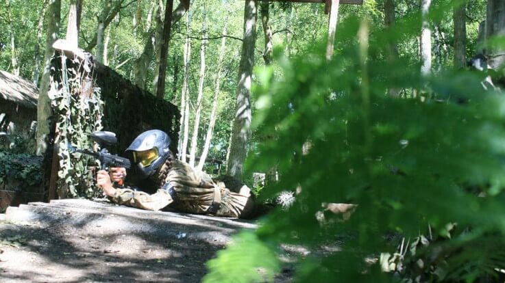 paintballer hiding behind woodland cover