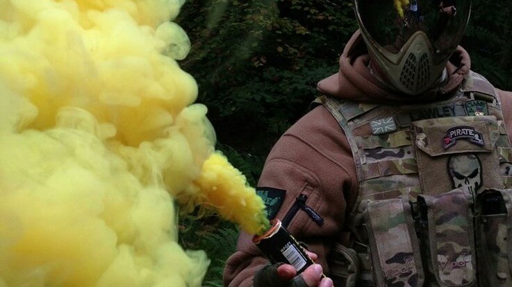paintballer holding lit smoke grenade