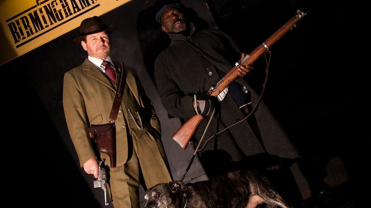 peaky pistol players standing under sign