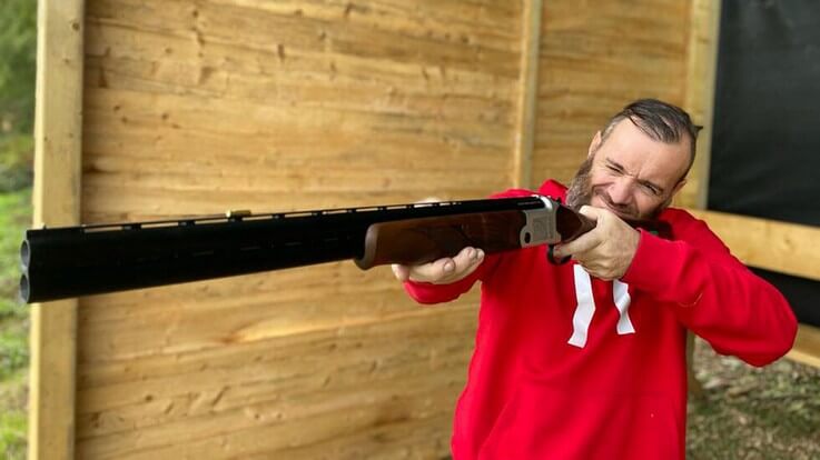 shooter in red jacket holding shotgun