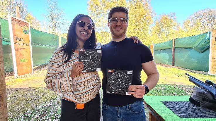 smiling couple holding rifle targets