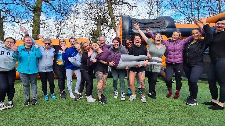 smiling ladies holding friend in front of inflatables