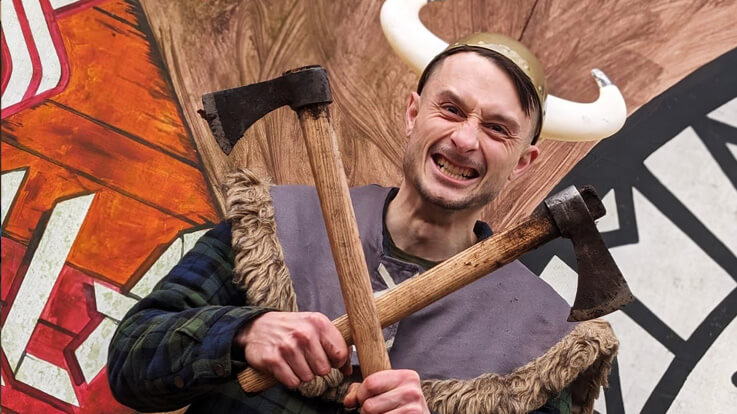 stag dressed as viking posing with axes