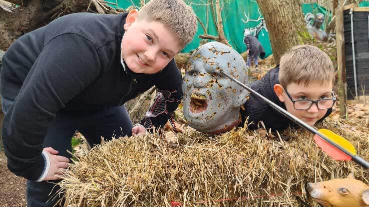 young archers posing with zombie target with arrow in head